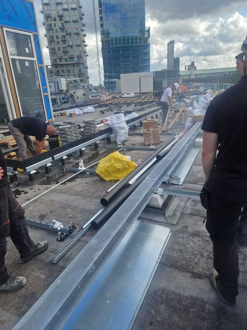 Dakrand en stalen profielen op een plat dak met hoogbouw op de achtergrond