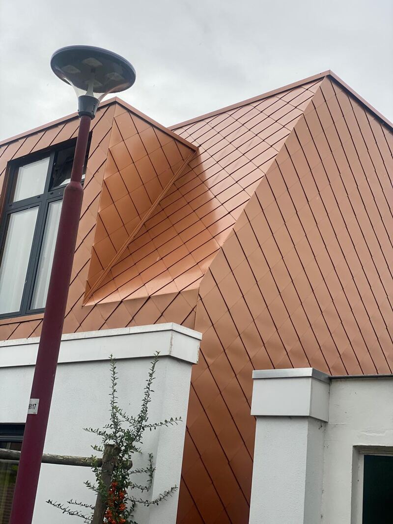 Gevelbekleding van koperkleurige panelen bij een dakkapel