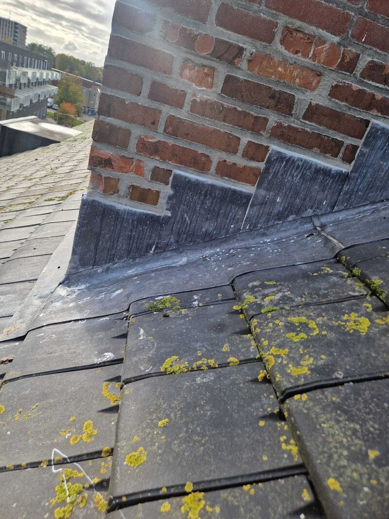 Loodslab rond een schoorsteen op een leien dak