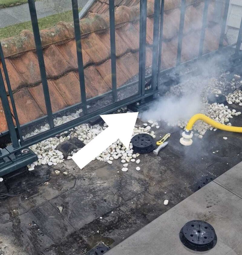 Rook bij een hekwerk op een dak met grind, een pijl wijst de plek aan