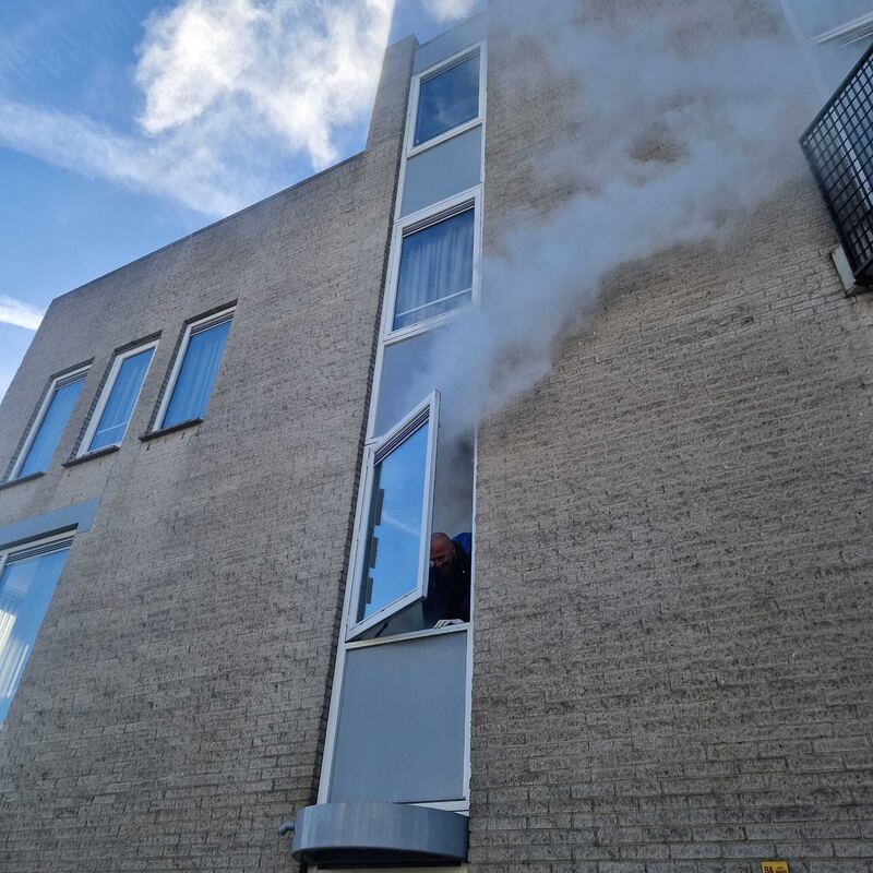 Rook komt uit een raampartij in een bakstenen gevel