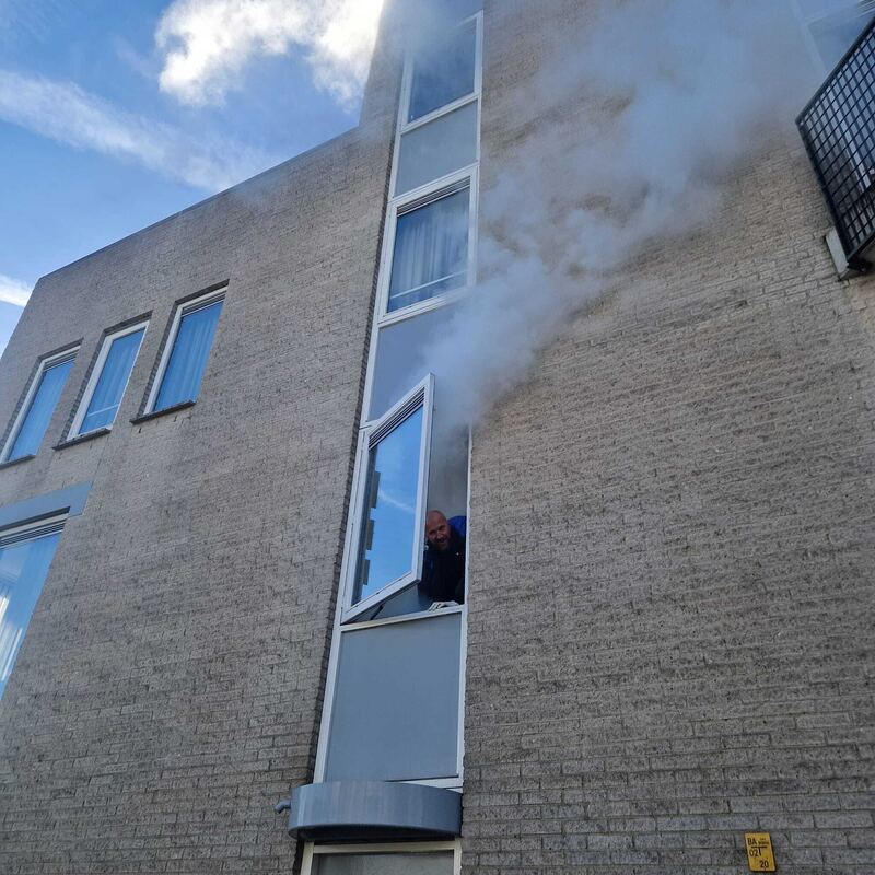 Rook komt uit een smalle raampartij in een gevel
