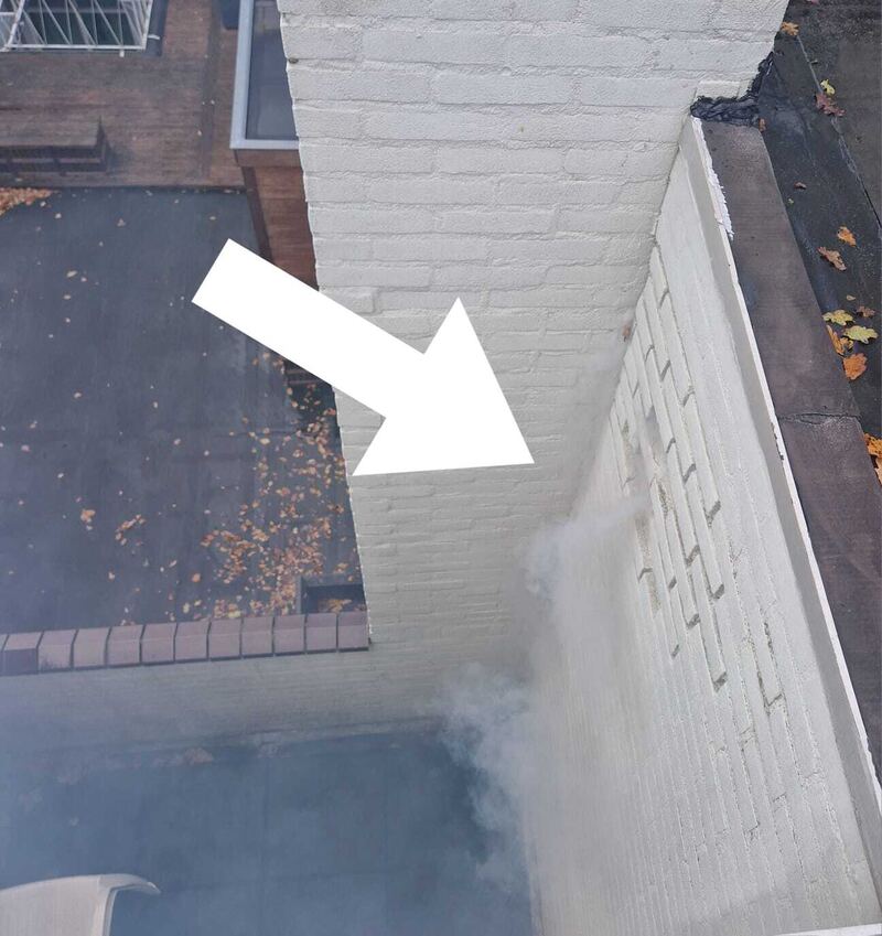 Rook langs een witte muur bij een dakopstand, een pijl wijst de plek aan