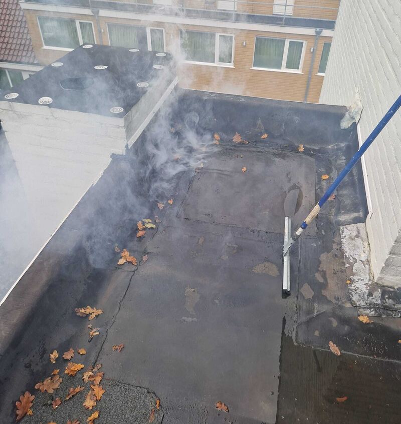 Rook op een plat dak met dakopstand en bladeren