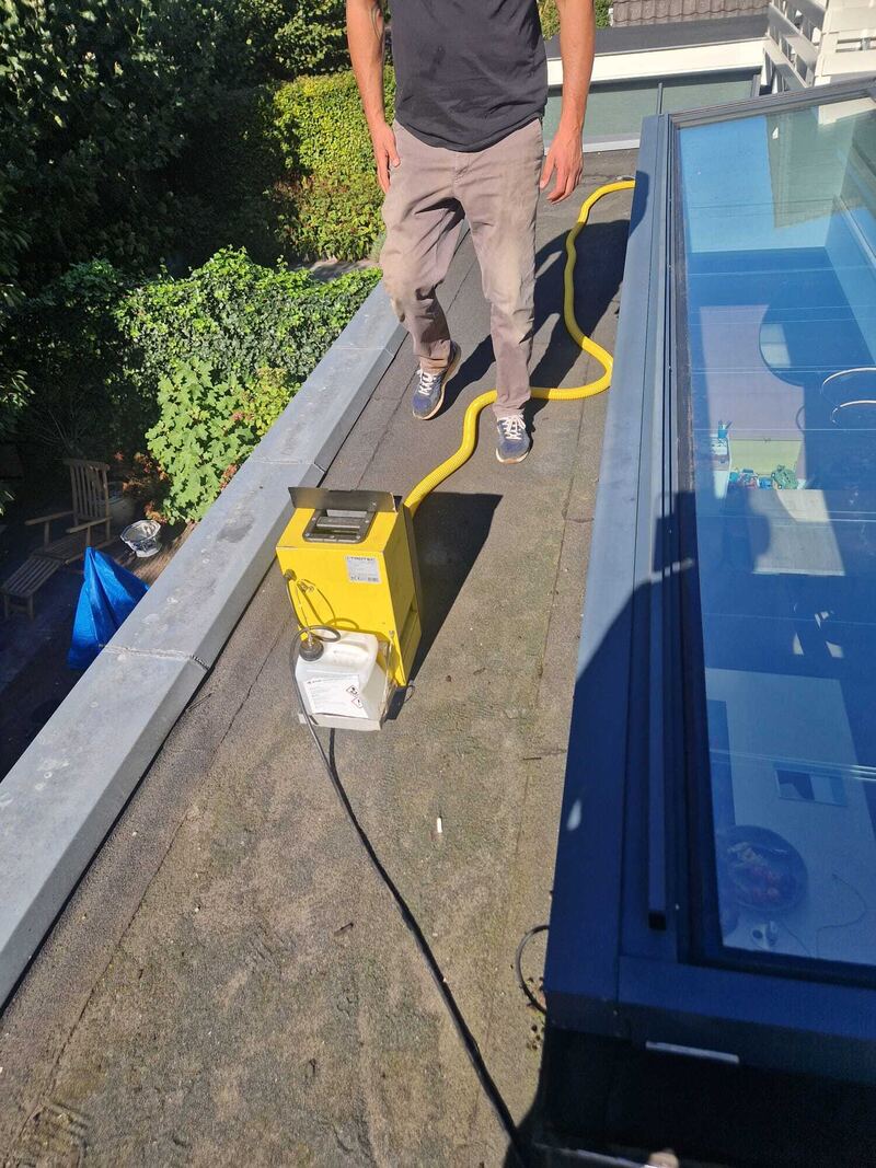 Rookmachine op een plat dak naast een glazen lichtstraat