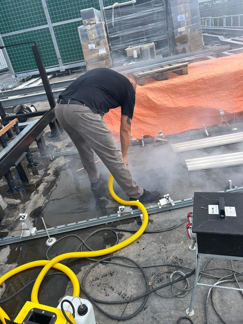 Rookproef op een plat dak naast een stalen constructie met oranje zeil
