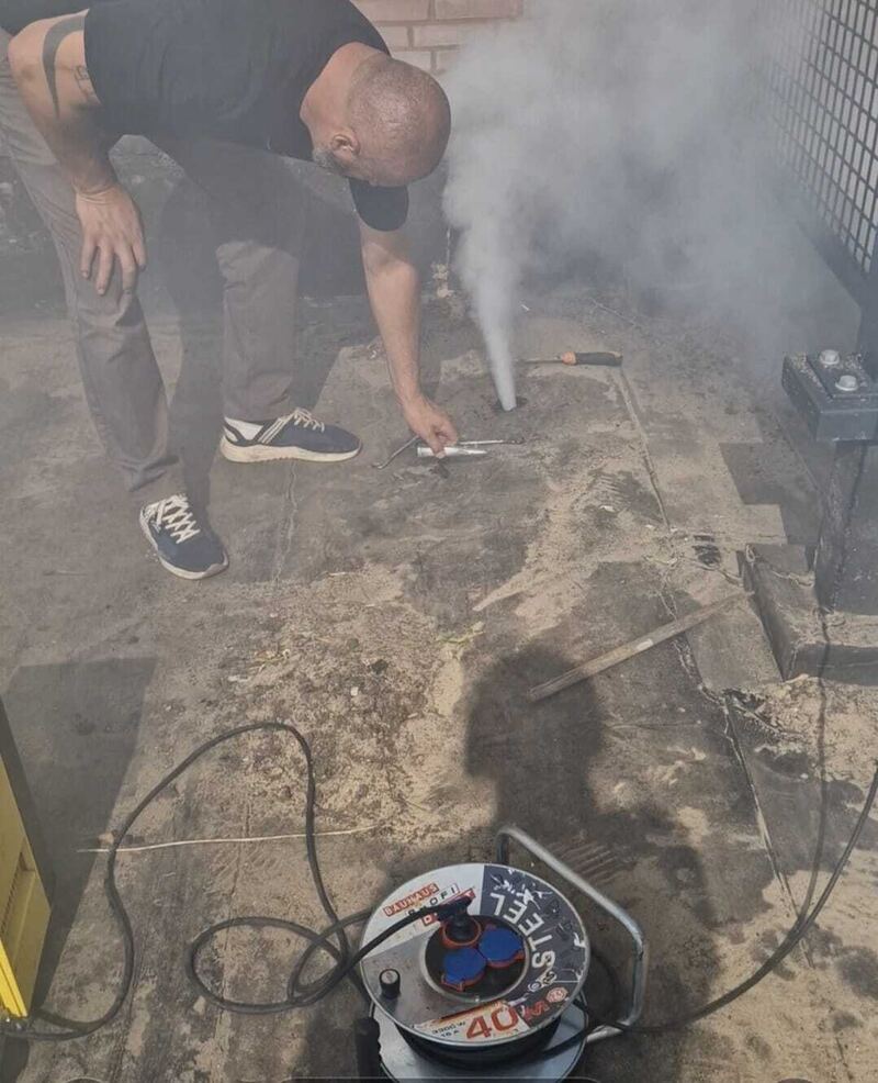 Specialist bij een rookproef op een plat dak met rook bij de dakdoorvoer