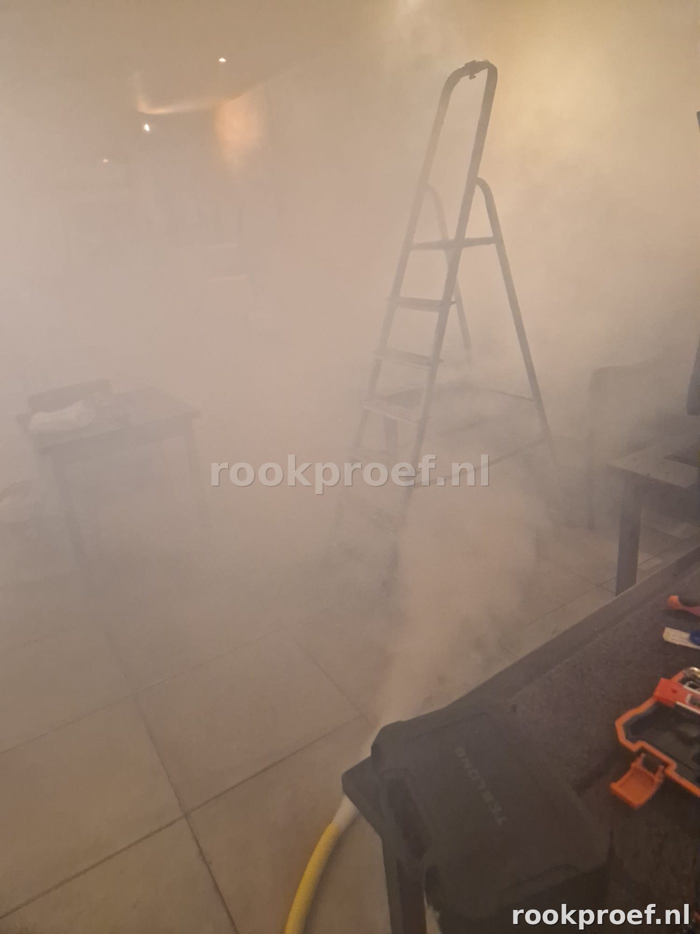 Rookproef in bedrijfsruimte met ladder en toolbox — rookgas vult volledige ruimte voor inspectie