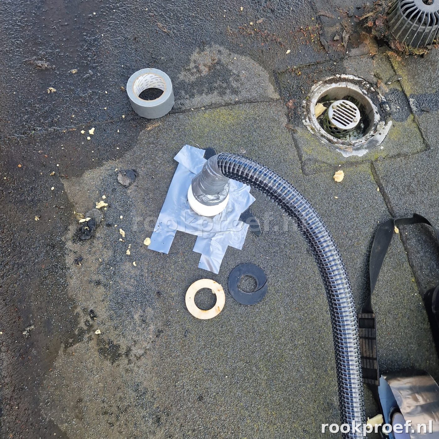 Dakdoorvoer afgedicht met tape voor rookproef — slang aangesloten op HWA afvoer plat dak bitumen