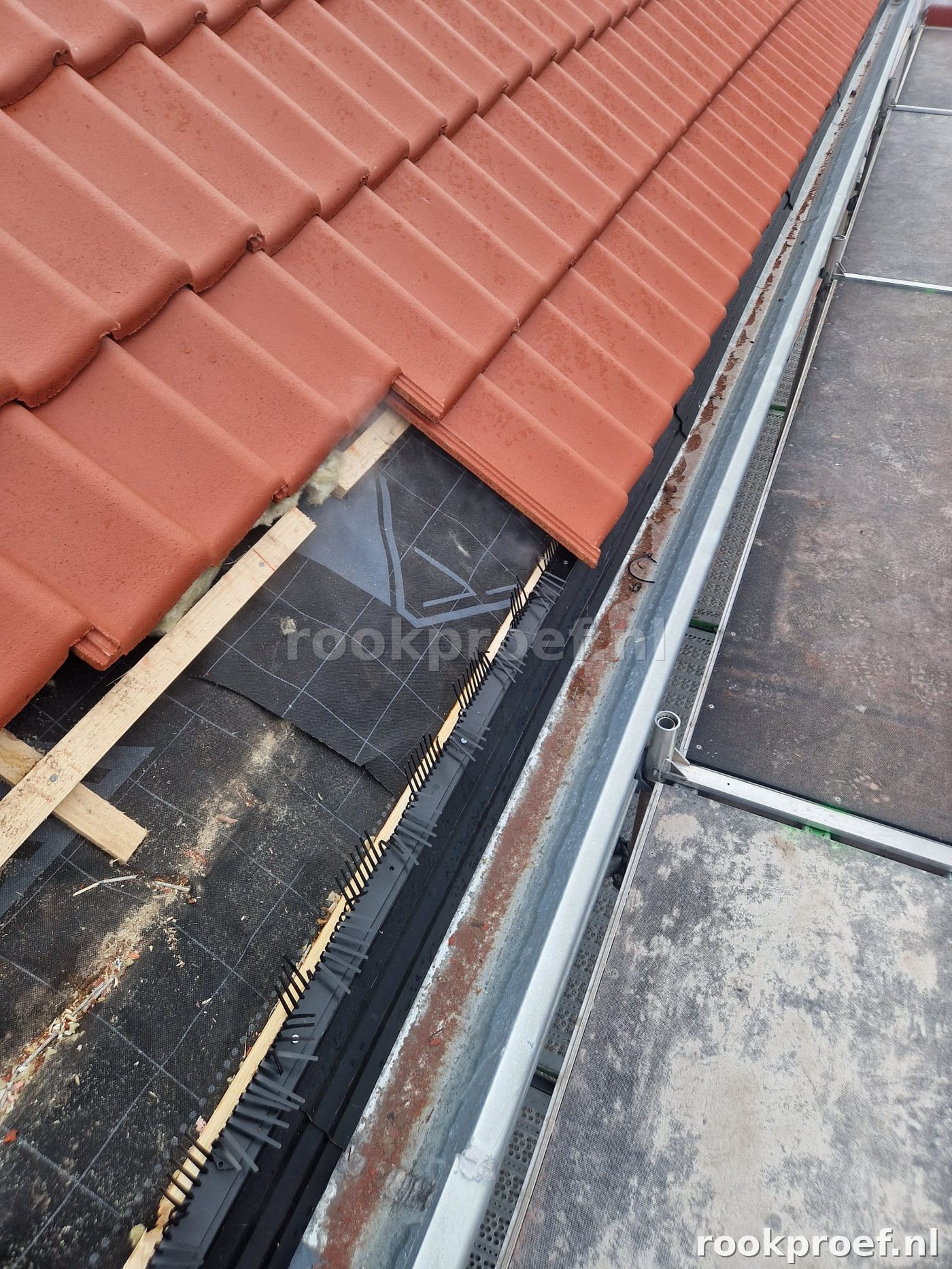Dakpannen gedeeltelijk verwijderd — ondervloer zichtbaar voor rookproef pannendak inspectie