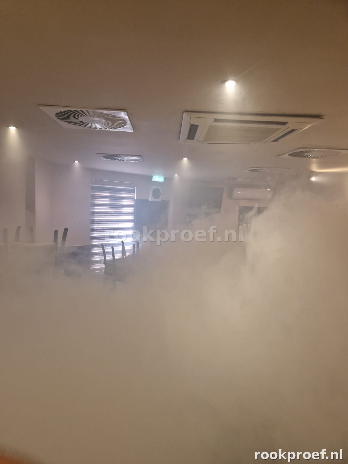 Rookgas vult restaurantzaal volledig — ventilatieroosters plafond zichtbaar tijdens rookproef