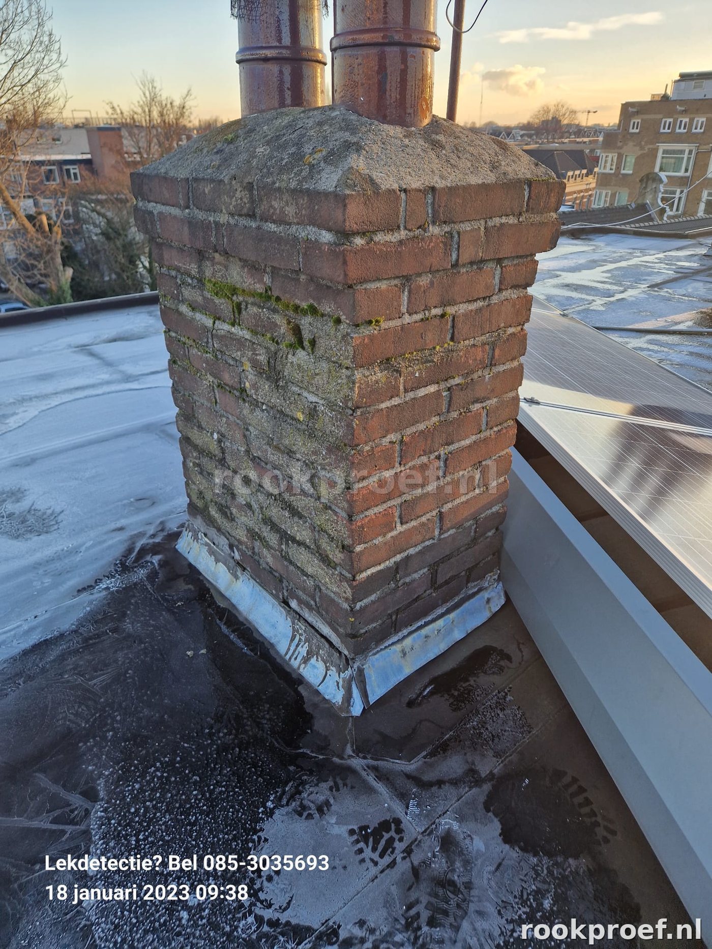 Verouderde schoorsteen op plat dak met vorstschade en mosgroei — rookproef schoorsteencontrole winter