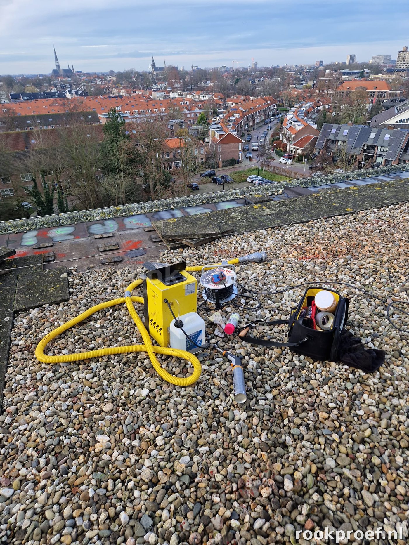 TROTEC rookgenerator op hoog grindlaag dak met stadsgezicht Leiden — complete rookproef opstelling