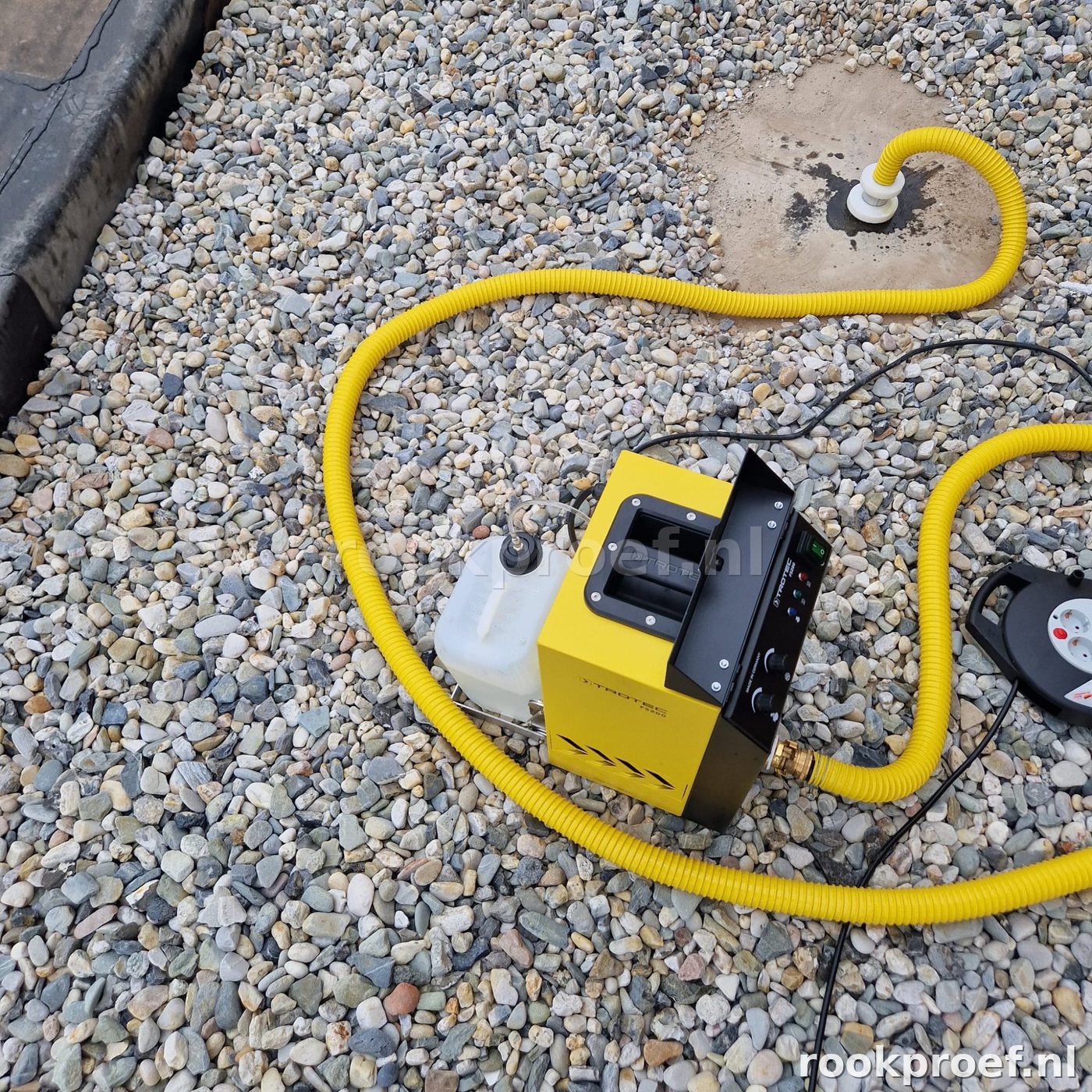 Trotec FS300 rookgenerator op grindlaag plat dak — gele slang dakdoorvoer aansluiting rookproef