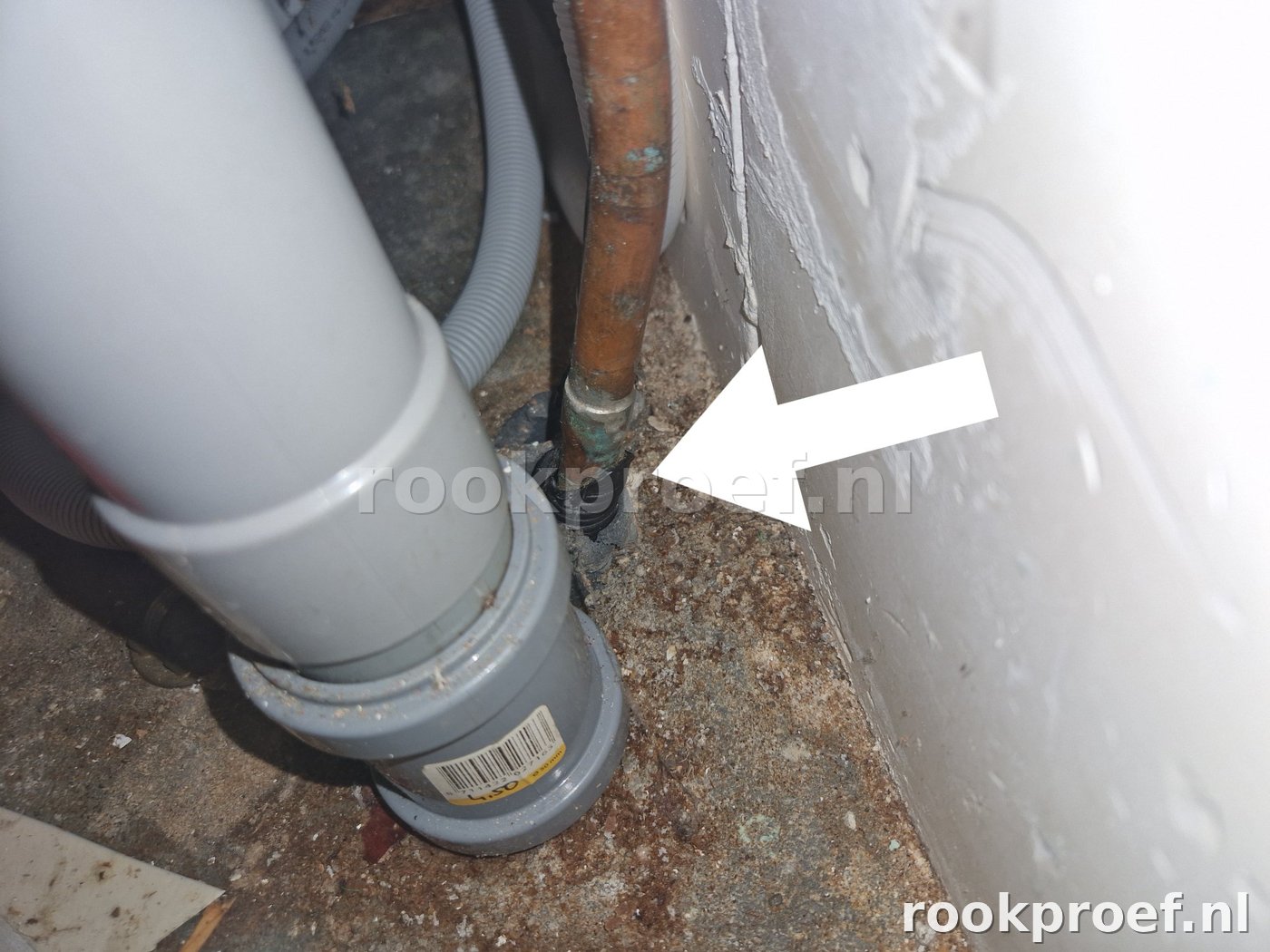 Close-up lekpunt rioolaansluiting — uitgedroogde koppelring bij koperen leiding gevonden via rookproef