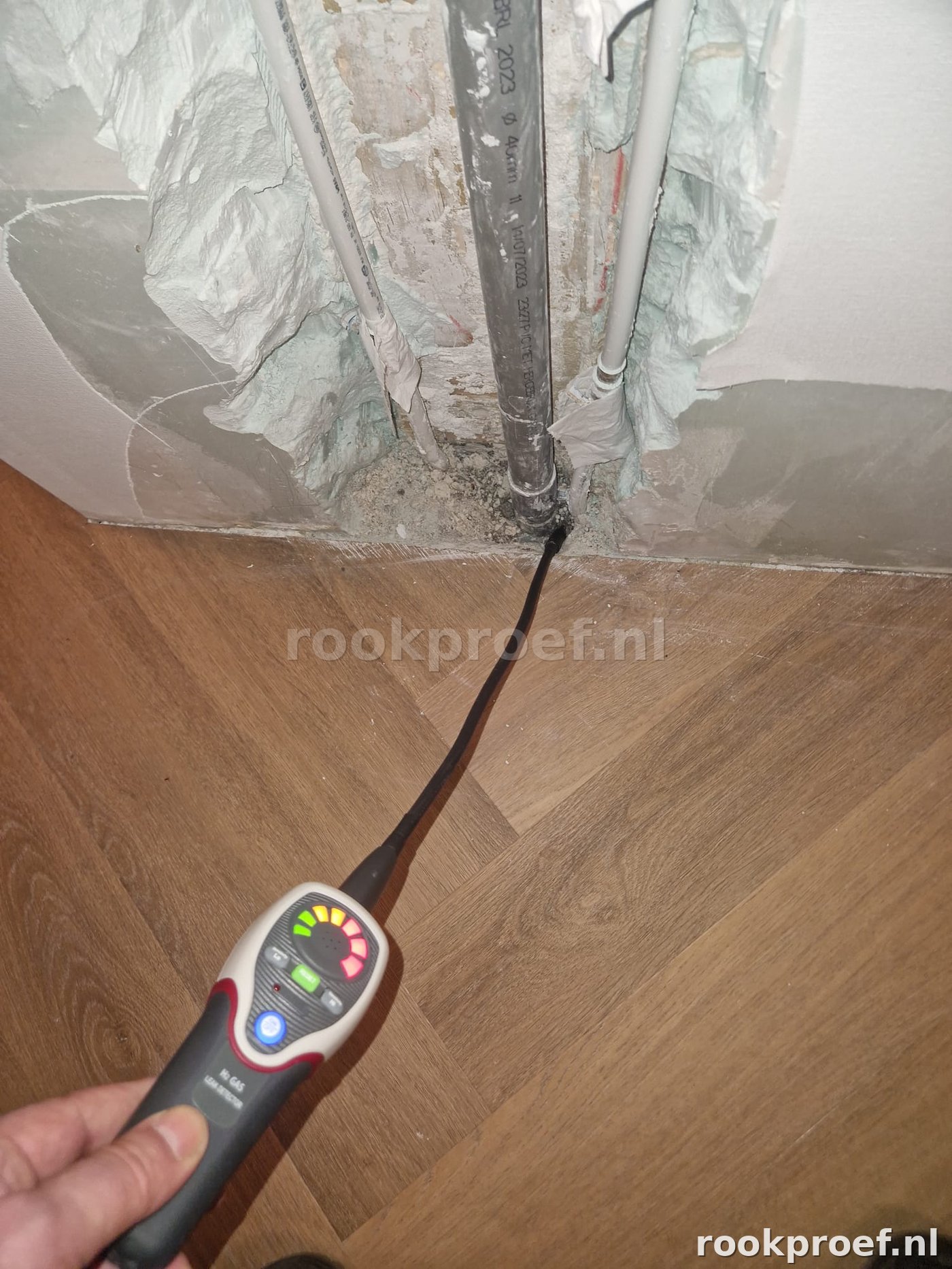 Gasdetector meet traceergas bij leidingdoorvoer in muur — exacte leklocatie opgespoord zonder breekwerk